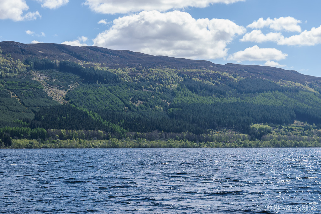 Loch Ness is long and narrow.  Low hills line both sides fo the loch. (1/250 sec at f / 7.1,  ISO 100,  55 mm, 18.0-55.0 mm f/3.5-5.6 ) May 09, 2017
